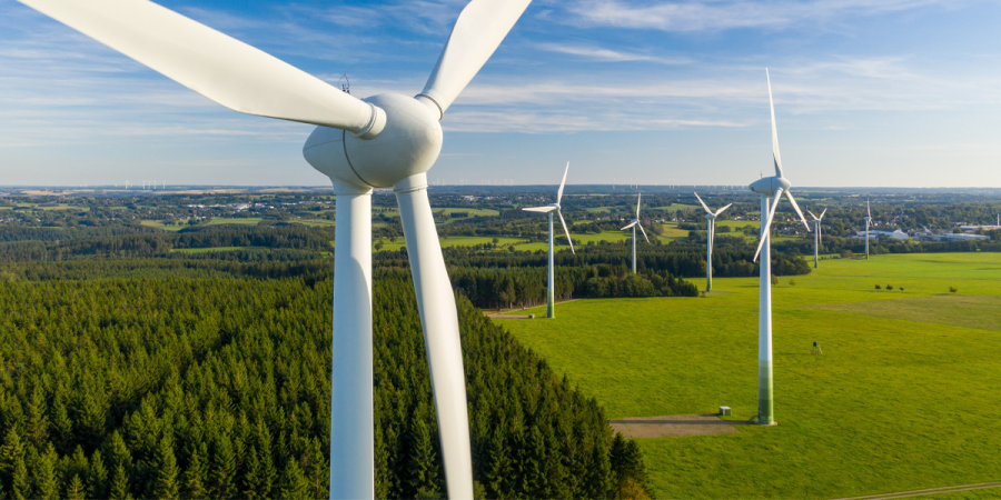 Luftaufnahme von Windkraftanlagen in einem grünen Feld das die nachhaltige Energieerzeugung symbolisiert