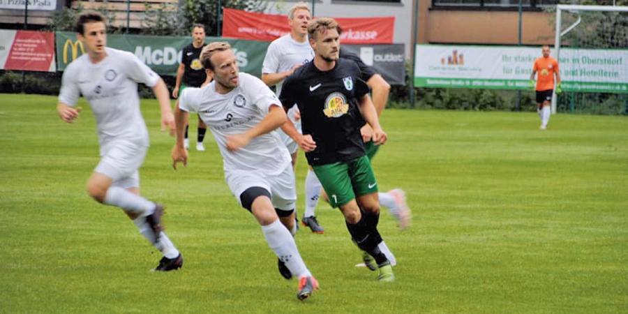 Mehrere Fußballspieler rennen während einem Spiel dem Ball hinterher 