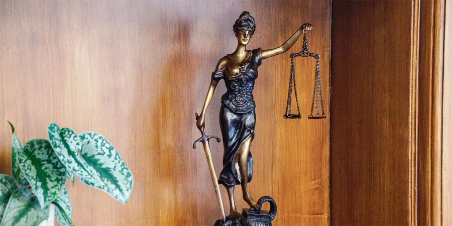 Statue der Justitia steht in einem Regal