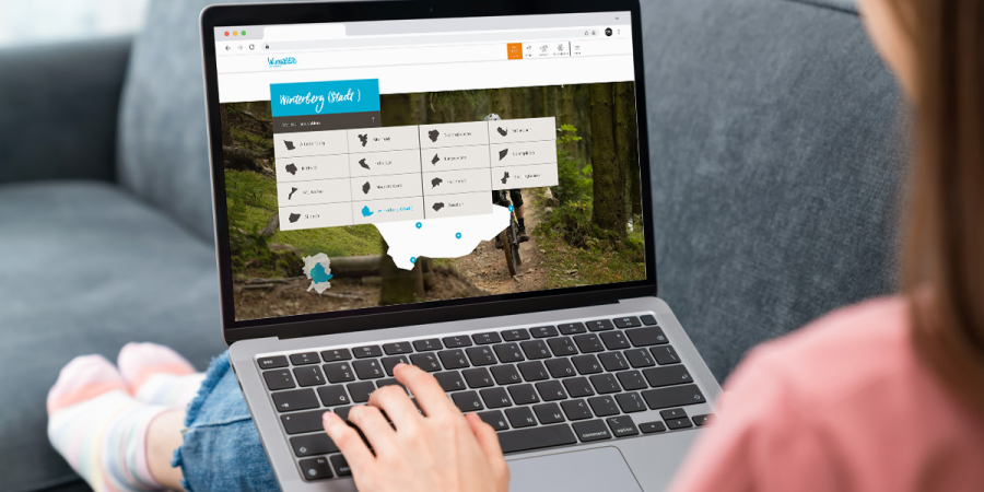 Eine Frau sitzt auf dem Sofa und sieht sich an ihrem Laptop die Website von Winterberg an